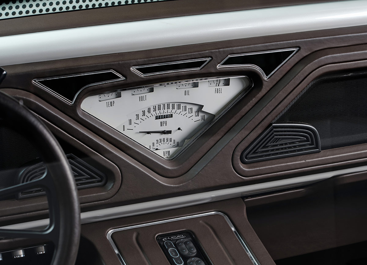 Custom-built triangular instrument cluster in a stitched leather dashboard.