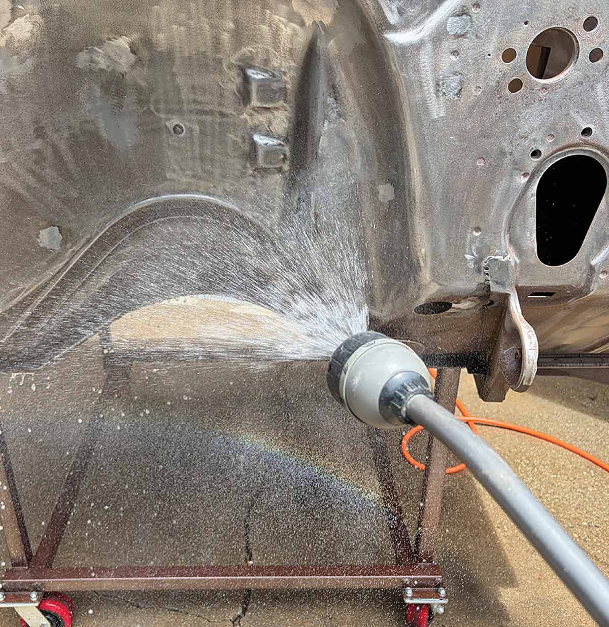 Rinsing the firewall with a water hose.
