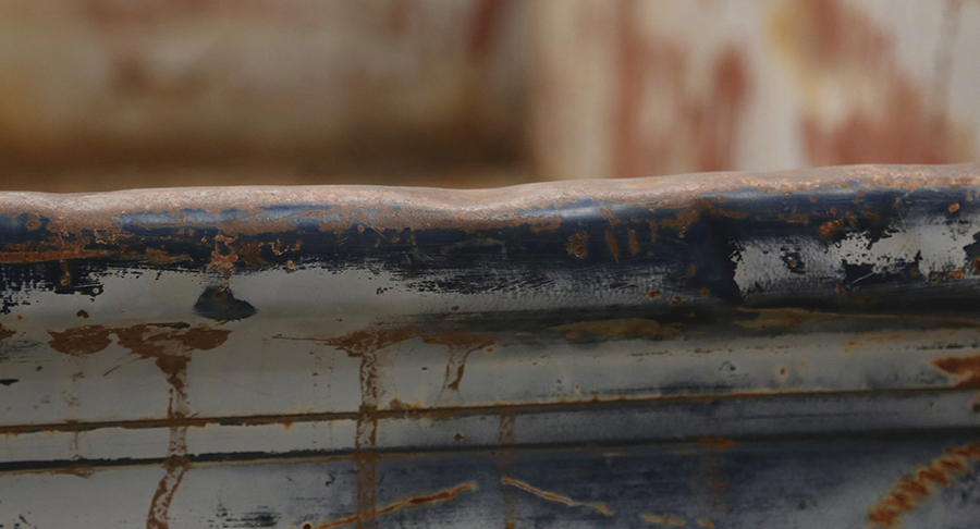 Dented top rail of a classic truck tailgate.