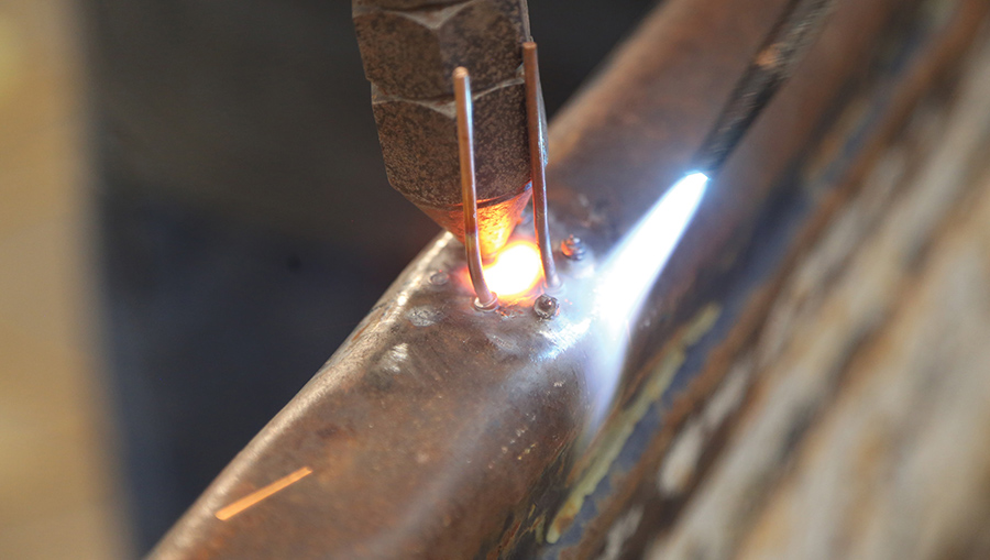 Heating metal around a weld stud with a torch.