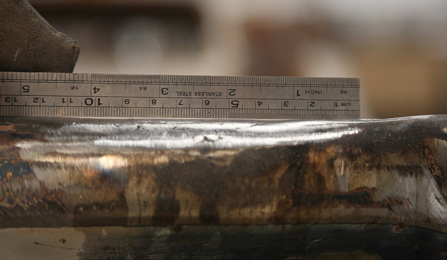 Checking tailgate rail flatness with a stainless steel ruler.