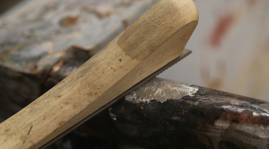 Filing down body solder with a body file.
