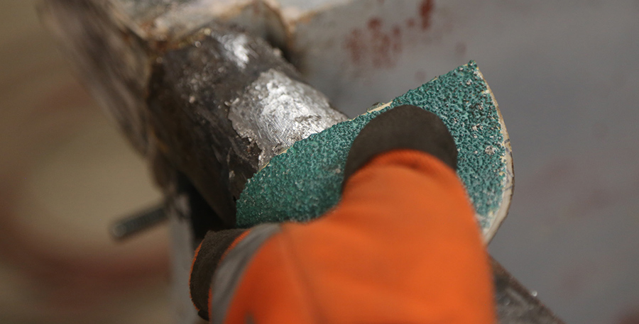 Hand sanding the repaired tailgate rail with green abrasive.