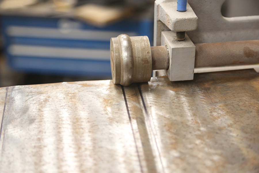 Rolling a rib into sheetmetal using a bead roller.