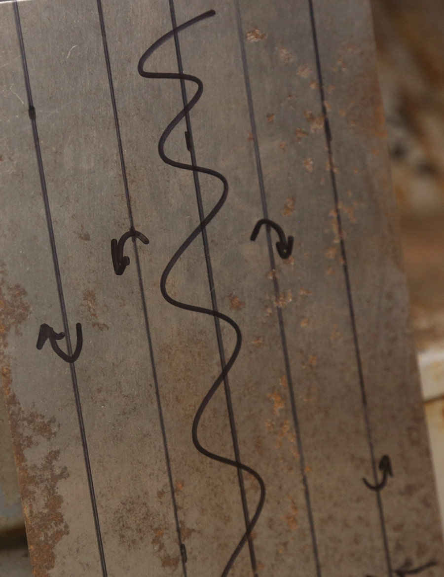Scribed bend lines and arrows on a metal patch.