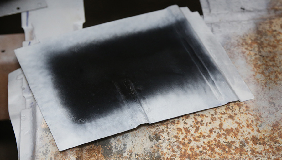 Applying weld-through coating to the edges of metal patches.