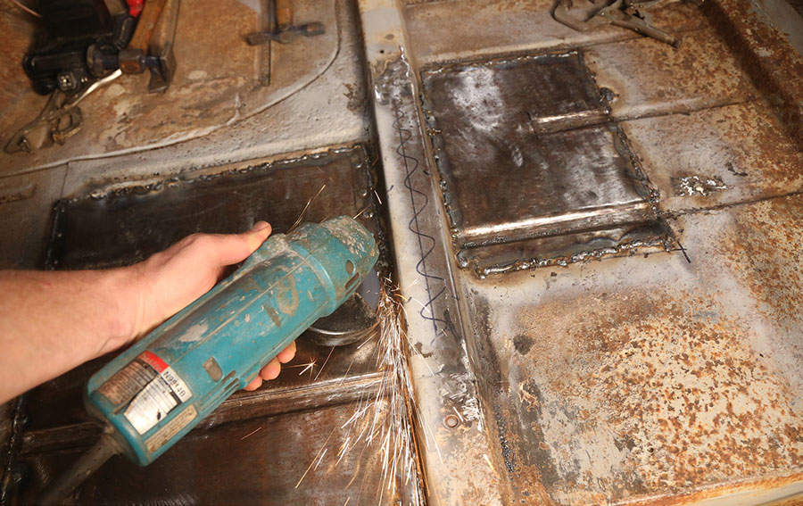 Grinding down floor welds with a power tool.