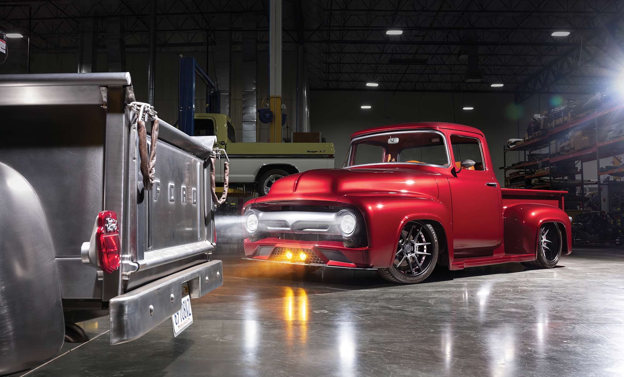 Front angle of the red truck with headlights on in a shop.