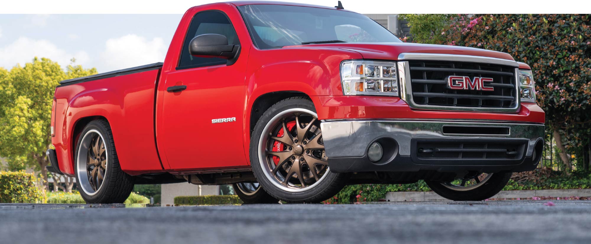 Red 2011 GMC Sierra single-cab pickup truck with custom wheels.